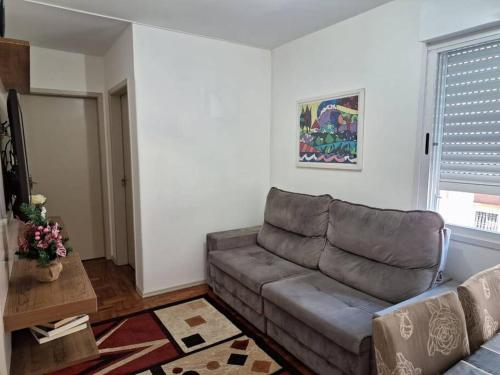 a living room with a couch and a window at Charmoso apartamento próximo ao Consulado EUA in Porto Alegre