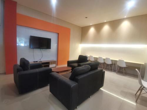 a meeting room with couches and a projection screen at Autumn Living Hotel in Surabaya