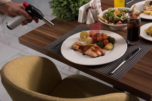 a table with a plate of food and a salad at İbos Hotels Izmir in Izmir