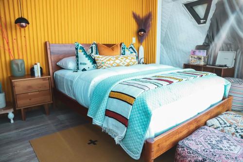 1 dormitorio con 1 cama grande y pared amarilla en Zia Geo Dome At El Mistico Ranch, Glamping, en Nogal
