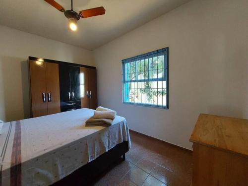 - une chambre avec un lit, un ventilateur et une fenêtre dans l'établissement Casa de Temporada - São Sebastião - Praia Barequeçaba - 500m da praia, à São Sebastião