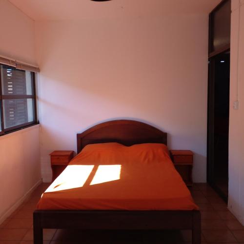 a bedroom with a bed with an orange blanket at Amplio departamento zona centro in Paraná