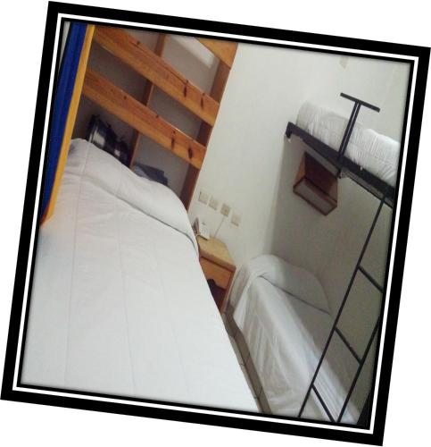Cette petite chambre comprend 2 lits et une croix sur le mur. dans l'établissement Hostal de Escandón, à Ciudad Victoria