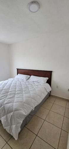 1 dormitorio con cama blanca y cabecero de madera en casa violeta norte, en Tuxtla Gutiérrez
