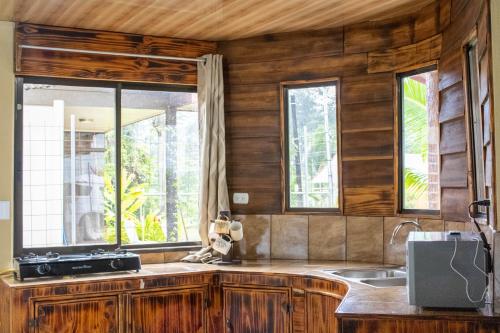 a kitchen with wooden walls and a sink and windows at Arenal NAE Home in Fortuna
