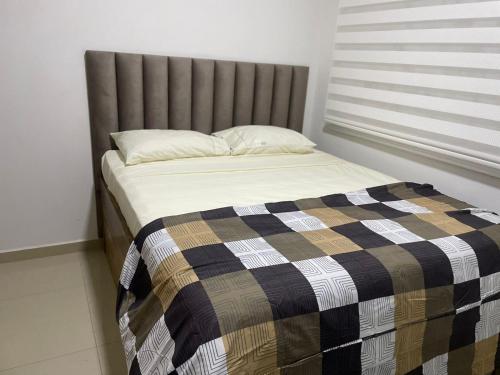 Una cama con manta y una ventana en una habitación en CONDOMINIO EN SANTA MARTA CON SALIDA AL MAR, en Santa Marta