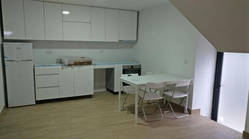 a kitchen with white cabinets and a table and chairs at Areias Village in Vale de Cambra