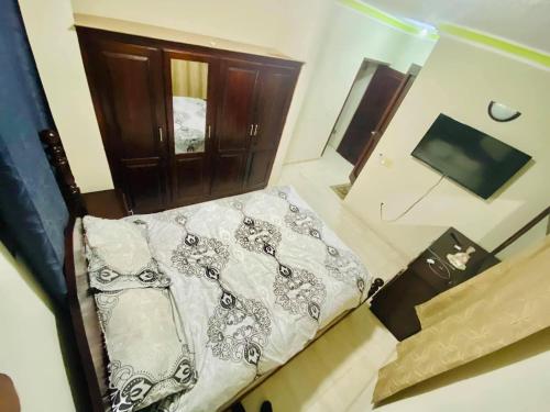 a small bed in a room with a wooden door at Le Bigot Appartements in Gonaïves