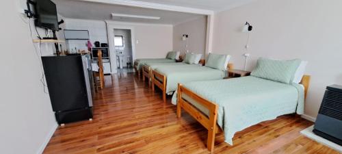 a room with four beds and a flat screen tv at Cabañas OtilNau in Puerto Natales