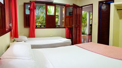 2 łóżka w pokoju z czerwonymi zasłonami w obiekcie Playa Mareygua Hostal w mieście Buritaca