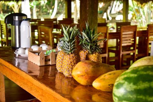 a table with pineapple and other fruits on it at Playa Mareygua Hostal in Buritaca