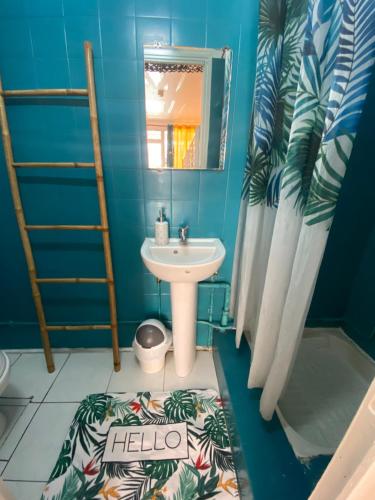 uma casa de banho azul com um lavatório e um espelho em Auberge K-WAN Hostel em Deshaies