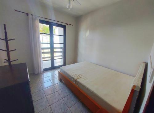 ein Schlafzimmer mit einem Bett und einem großen Fenster in der Unterkunft Casa de praia in Itapoa