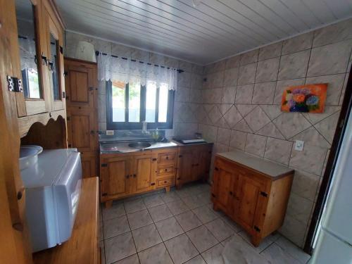 eine Küche mit Holzschränken, einem Waschbecken und einem Fenster in der Unterkunft Casa de praia in Itapoa