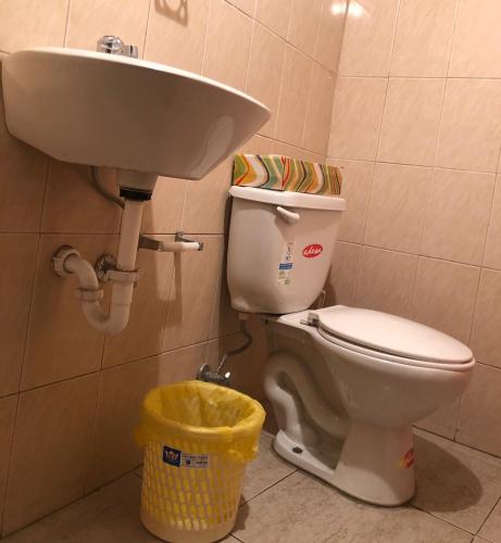 a bathroom with a toilet and a sink and a trash can at HOSPEDAJE las PRIMICIAS RIOBAMBA 105 in Riobamba