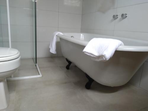 帕拉蒂的住宿－Fazenda do Bosque - Pousada e Capril，白色的浴室设有浴缸和卫生间。