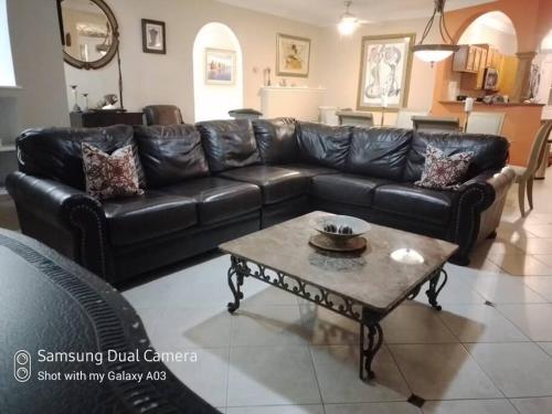 - un canapé en cuir noir dans le salon avec une table basse dans l'établissement Villa Victoria Pool Retreat, à Long Bay Hills
