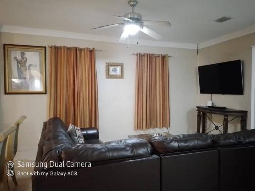 a living room with a leather couch and a flat screen tv at Villa Victoria Pool Retreat in Long Bay Hills