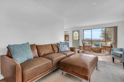 a living room with a brown couch and a table at Seaglass at Pambula Beach in Pambula Beach