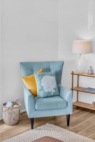 a blue chair with a pillow in a living room at Seaglass at Pambula Beach in Pambula Beach