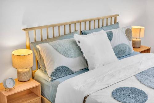 a bed with blue and white pillows and two lamps at Seaglass at Pambula Beach in Pambula Beach