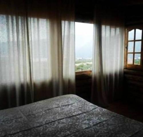 a bedroom with a bed and a window with curtains at Cabañas IsaMart in Potrerillos