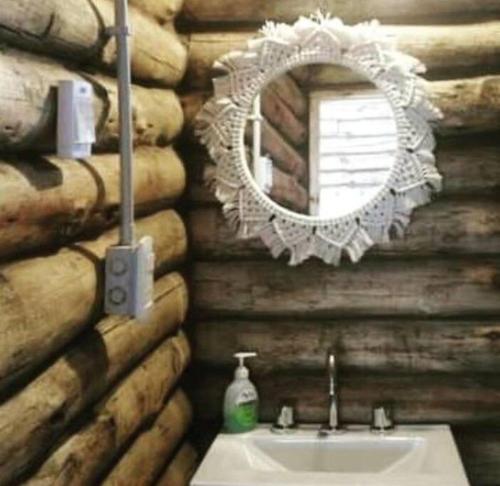 a bathroom with a sink and a mirror on a log wall at Cabañas IsaMart in Potrerillos