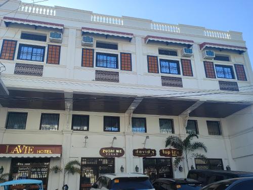 ein großes weißes Gebäude mit davor geparkt in der Unterkunft LaVie Hotel in Vigan City