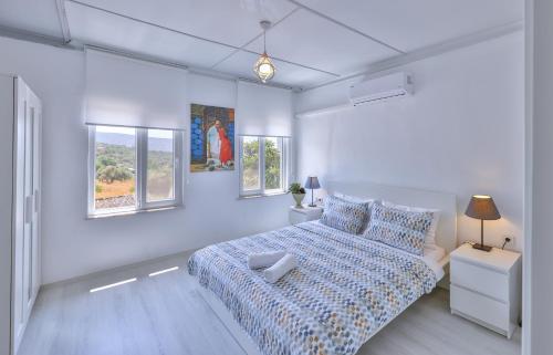 a white bedroom with a bed and two windows at AGACH Apart 1 & 2 in Milas