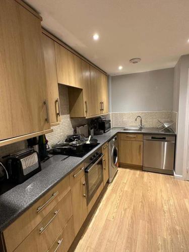 a kitchen with wooden cabinets and stainless steel appliances at Contemporary, Stylish Apartment in Weston in Worle