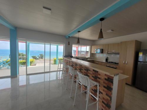 a kitchen with a bar with chairs and a view of the ocean at 321 Surprise Beach house and Glamping in Providencia
