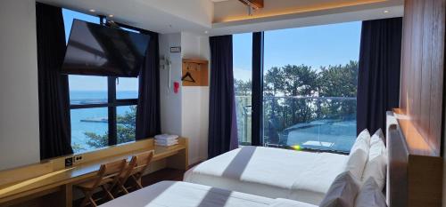 1 dormitorio con cama y escritorio con ventana grande en The Club Hotel Gijang Yeonhwari en Busan