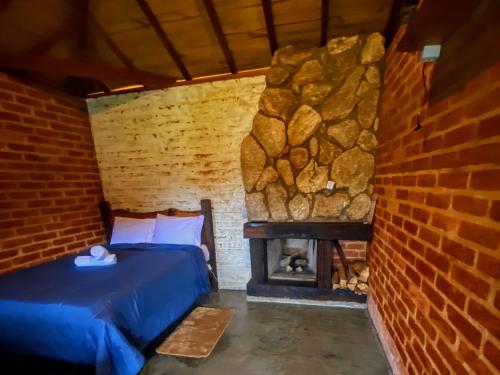 a room with a bed and a stone fireplace at pousada do caneca in Senador Amaral