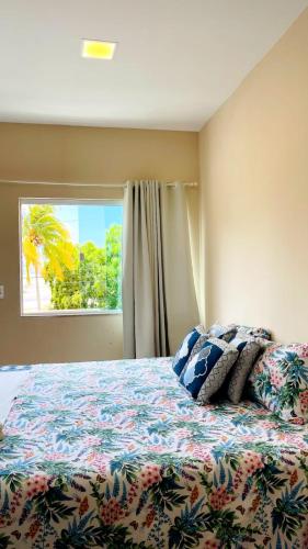 a bedroom with a bed with pillows and a window at Pousada OPA - O Paraíso é Aqui Abrolhos in Caravellas