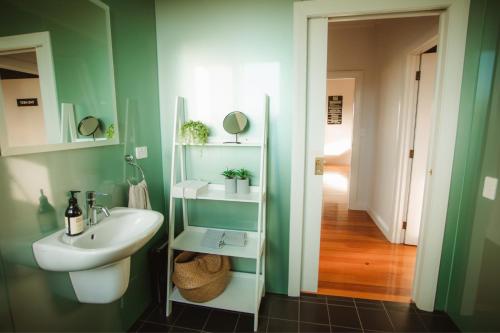 ein Badezimmer mit grünen Wänden, einem Waschbecken und einem Spiegel in der Unterkunft The Cellar Door - Blenheim Holiday Home in Blenheim
