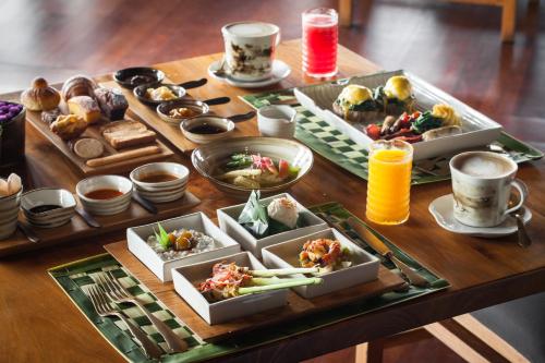 een houten tafel met borden met eten en drinken erop bij Bulgari Resort Bali in Uluwatu