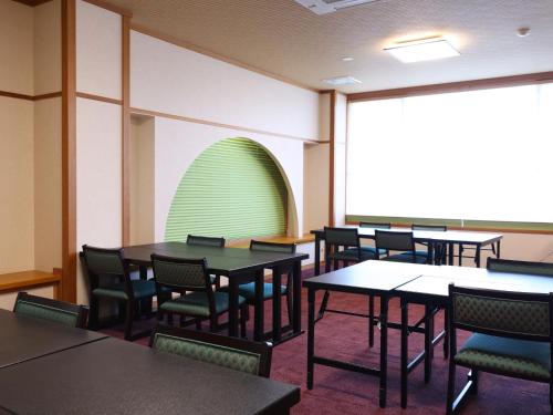 a dining room with tables and chairs and a green wall at Hotel Asafuji in Fujikawaguchiko