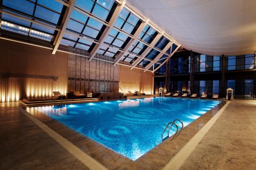 a large swimming pool in a building with windows at Hilton Suzhou in Suzhou