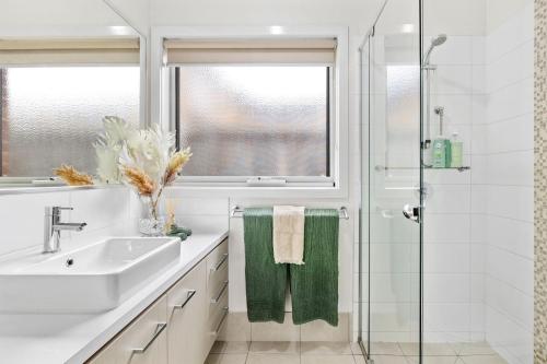 a white bathroom with a sink and a shower at Salty Sage Beach House in Torquay
