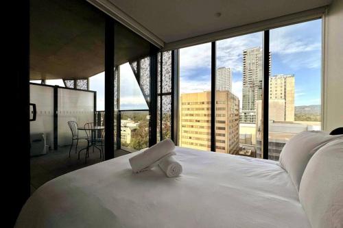 Cama blanca en habitación con ventana grande en City Chic Living: 1-BR APT Overlooking Rundle Mall en Adelaida