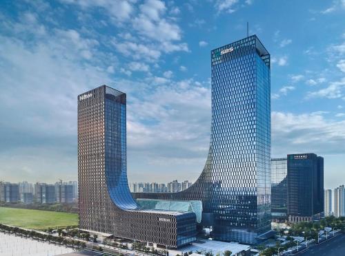 two tall skyscrapers in a city with at Hilton Suzhou in Suzhou