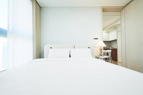 a bedroom with a large white bed and a living room at The November Stay In landmark in Incheon