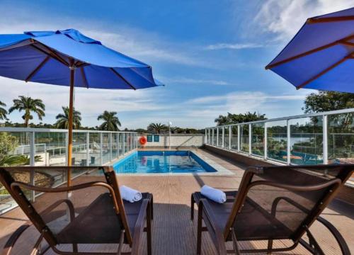 a balcony with two chairs and a swimming pool at Flat Pampulha orla prox Mineirão in Belo Horizonte