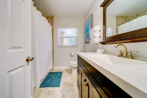 a bathroom with a sink and a toilet and a mirror at Palm Lagoon Clearwater - 3 bedroom Resort House with heated pool & SPA in Clearwater