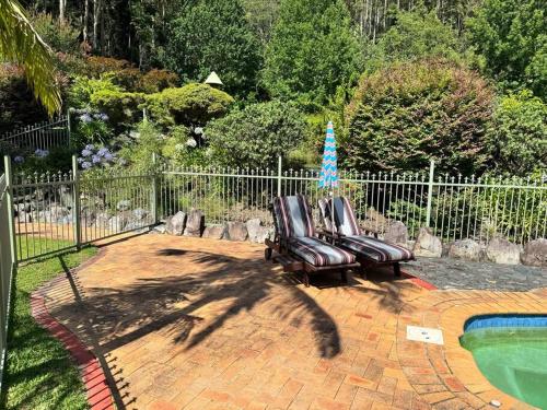 two leather chairs sitting next to a swimming pool at Oasis of Hope - Main House in Upper Orara