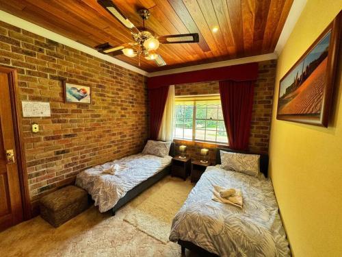a bedroom with two beds and a brick wall at Oasis of Hope - Main House in Upper Orara