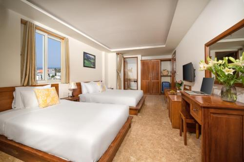 a hotel room with two beds and a desk at Titan Hotel Da Nang in Da Nang