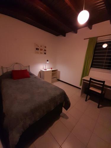 1 dormitorio con cama, mesa y ventana en Duplex tipo Casa Mendoza en Villa Hipódromo
