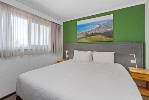 - une chambre avec un lit blanc et un mur vert dans l'établissement Apollo Bay Motel & Apartments, BW Signature Collection, à Apollo Bay