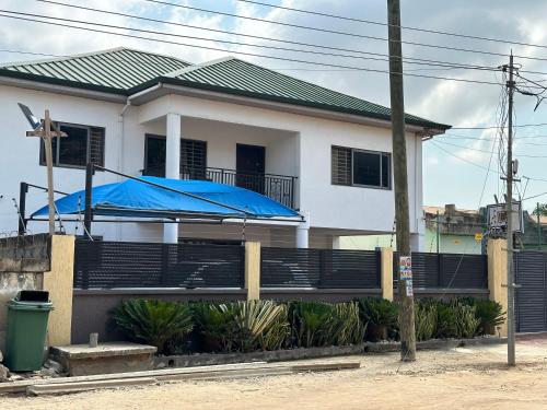 une maison blanche avec une tare bleue devant elle dans l'établissement RICHGIFT HOMES, à New Weija